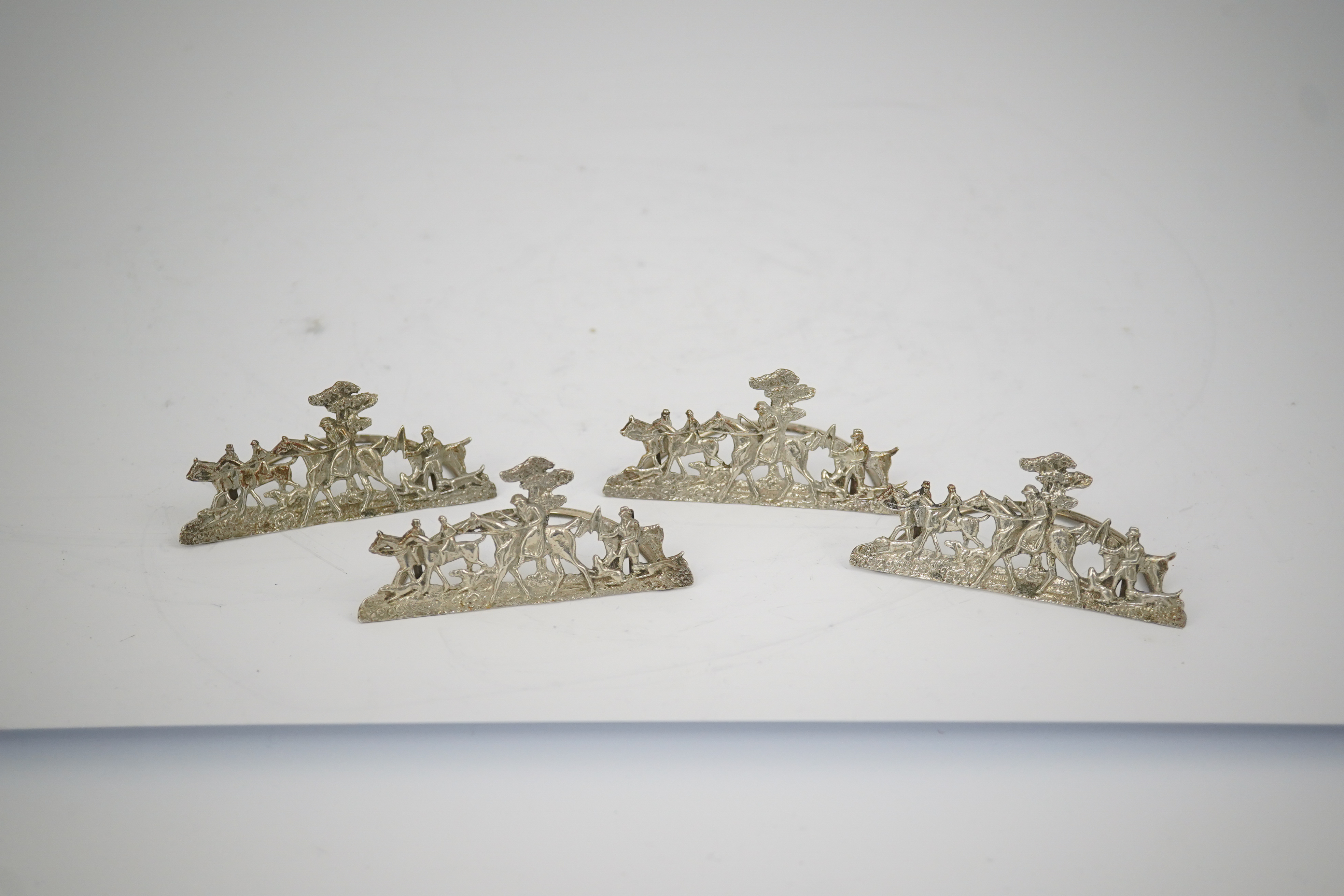 A set of four Edwardian pierced silver 'hunting scene' menu holders, by Stuart Clifford